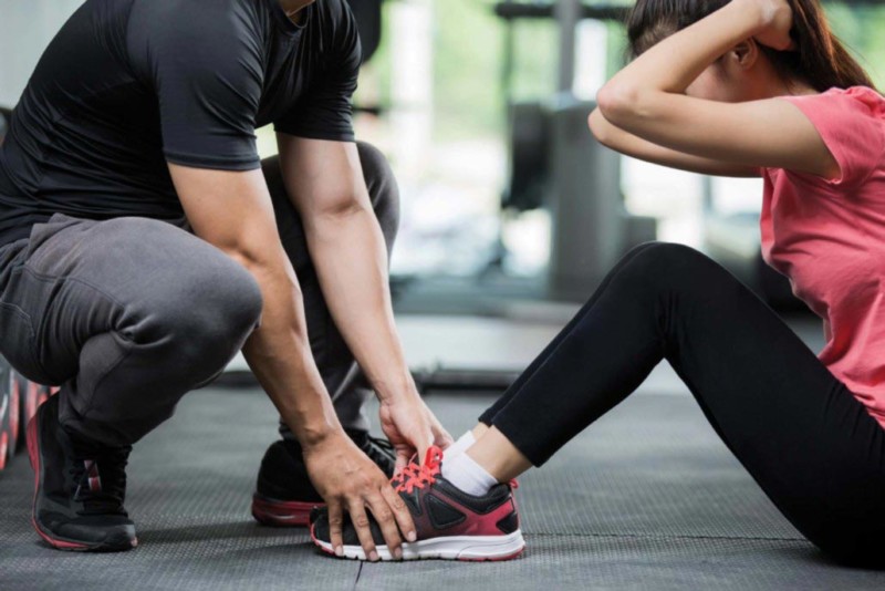trainer helping young women do sit ups